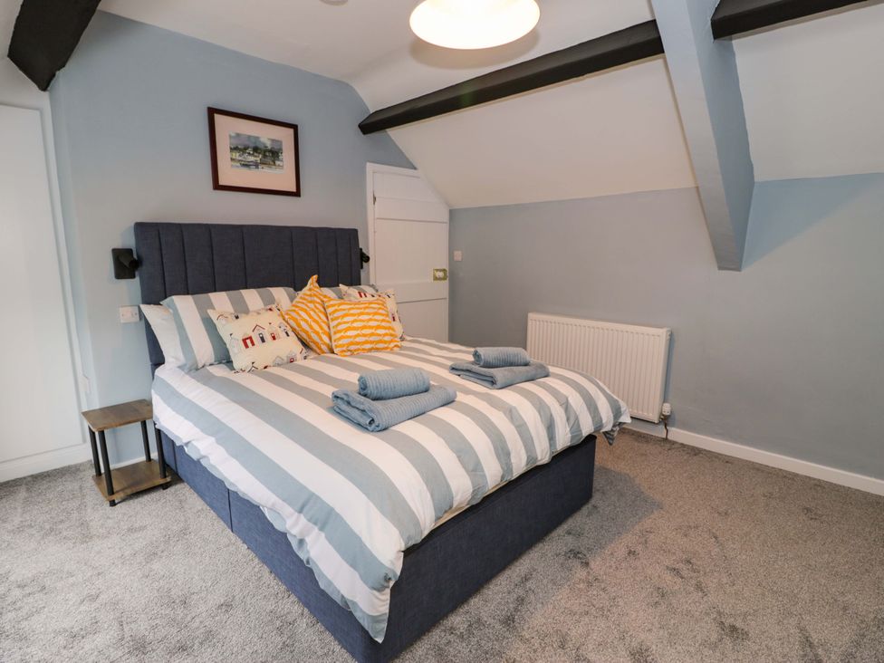 A bedroom with a bed and towels at Rosemary Cottage 1 Tywyn