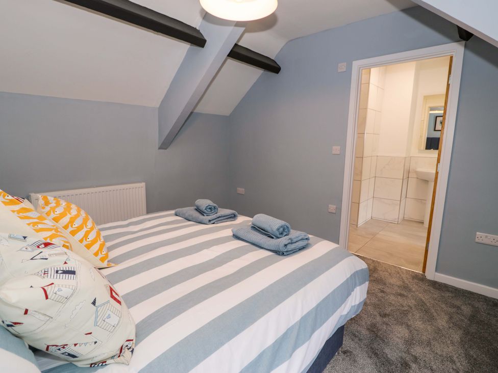 A bedroom with a bed and towels at Rosemary Cottage 1 in Tywyn