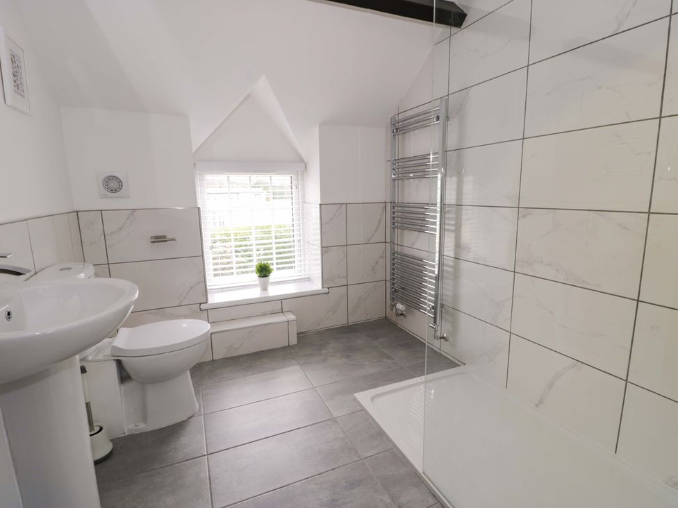 A bathroom with a wash basin, toilet, and shower at Rosemary Cottage 1 Tywyn