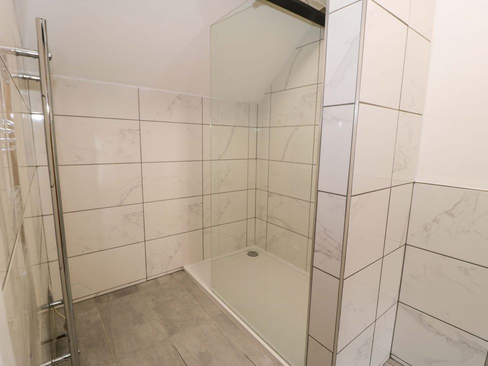 A shower area with tiled walls and floor at Rosemary Cottage 1 Tywyn
