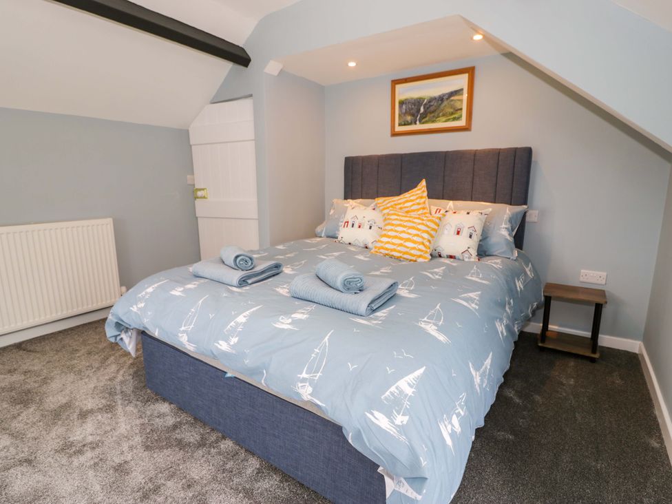 A bedroom with a bed and bedside table at Rosemary Cottage 1 in Tywyn