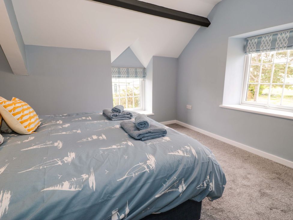 A bedroom with a bed and windows at Rosemary Cottage 1 Tywyn