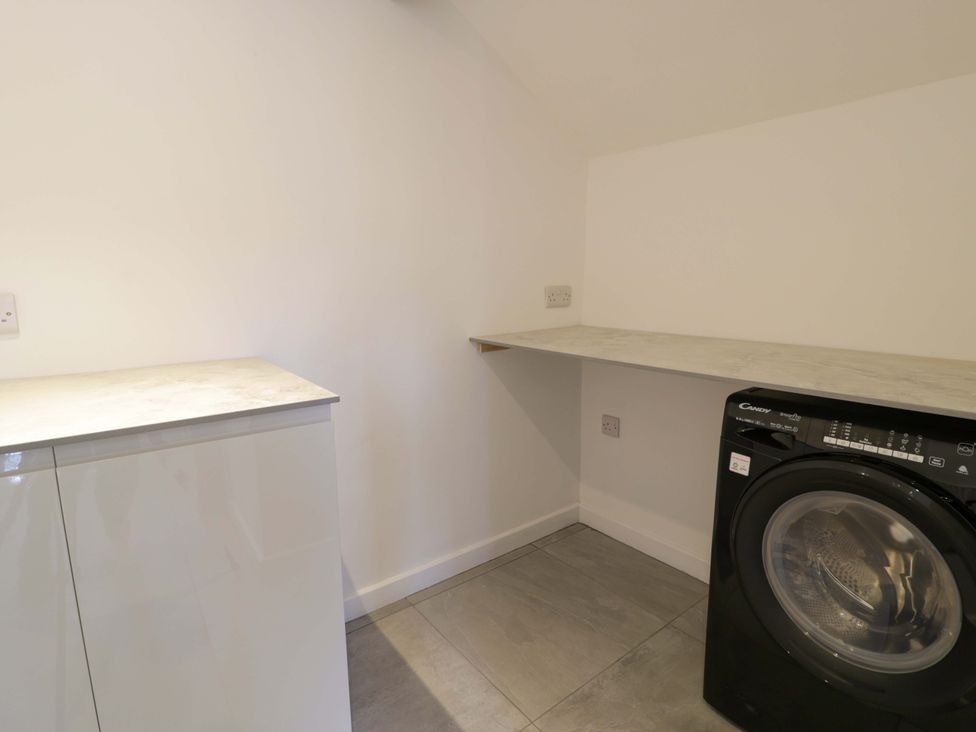 A laundry room with a washing machine and worktop at Rosemary Cottage 1 Tywyn
