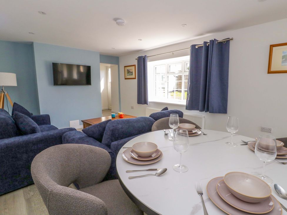 A living room with a sofa and dining table at Rosemary Cottage 1 Tywyn