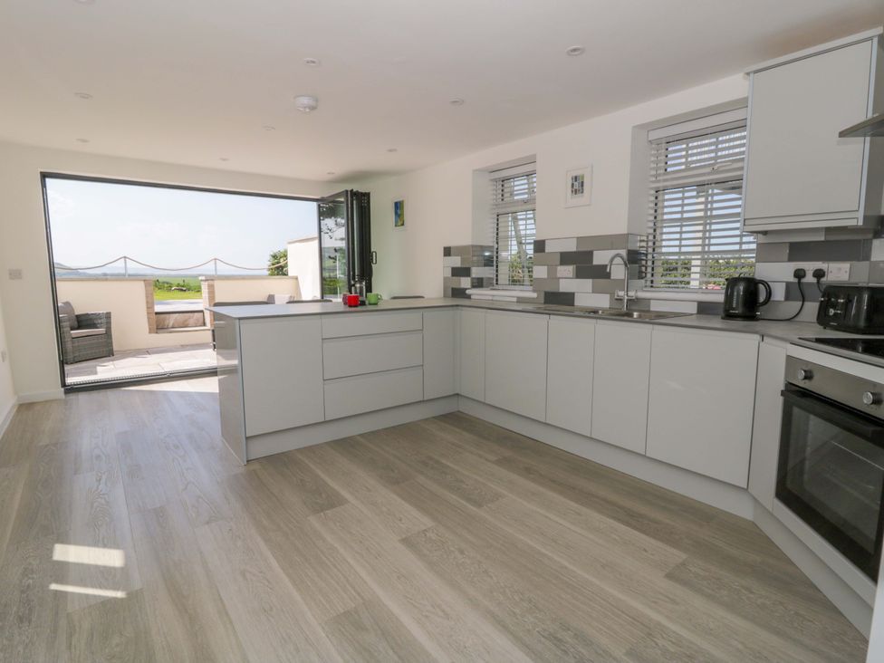 A kitchen with cabinets and a sink at Rosemary Cottage 1 Tywyn