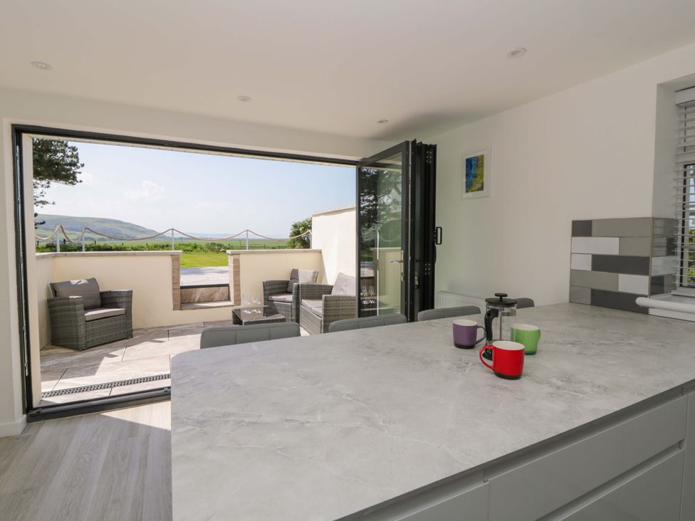 A kitchen with a view of outdoor seating at Rosemary Cottage 1 Tywyn