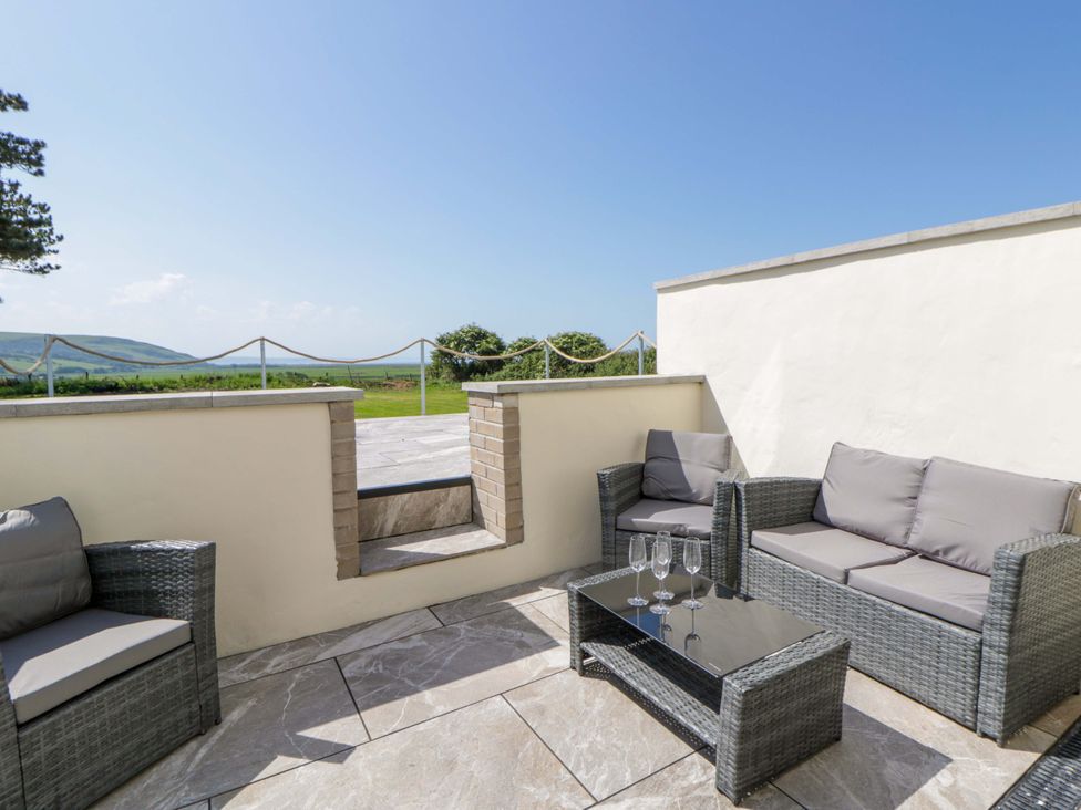 An outdoor patio with a sofa set and coffee table at Rosemary Cottage 1 in Tywyn