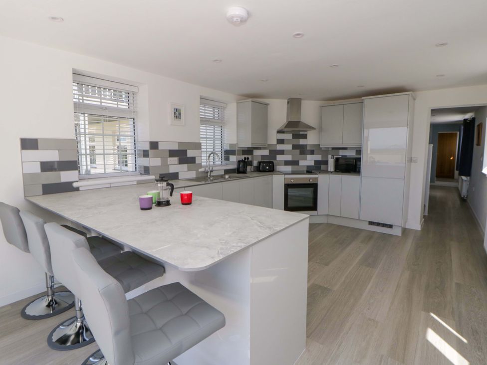 A kitchen with modern cabinets and appliances at Rosemary Cottage 1 Tywyn