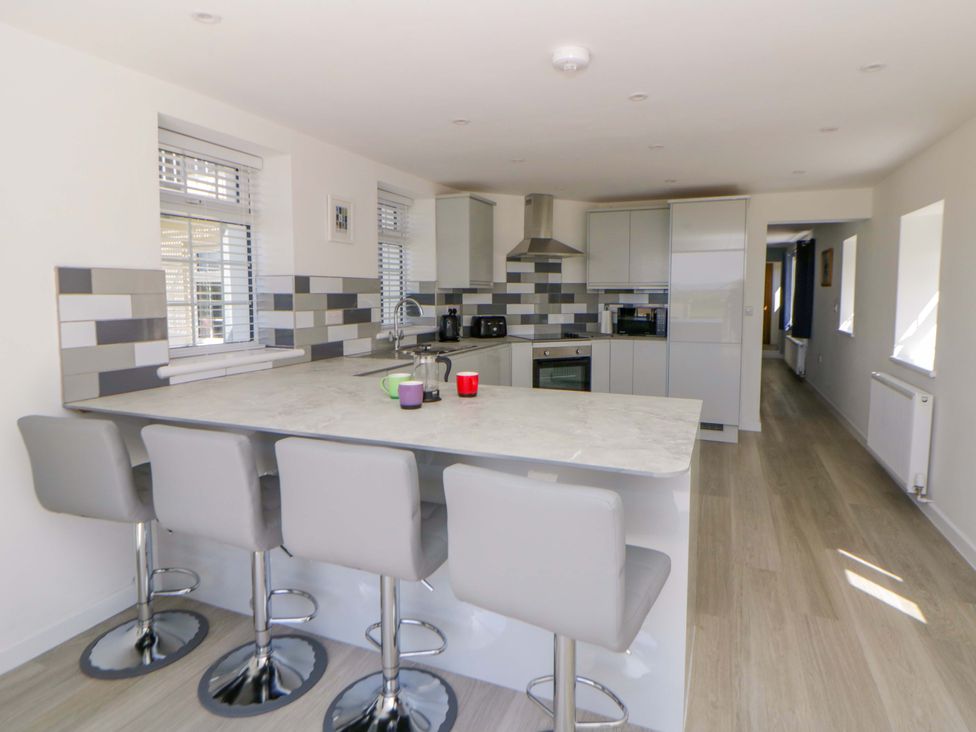 A kitchen with bar stools and countertop at Rosemary Cottage 1 Tywyn