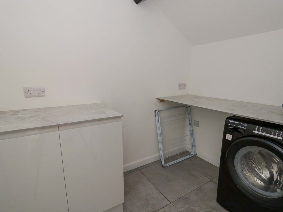 A laundry room with a washing machine and counter space at Rosemary Cottage 1 Tywyn