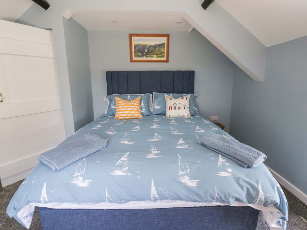 A bedroom with a bed and bedside table at Rosemary Cottage 1 in Tywyn