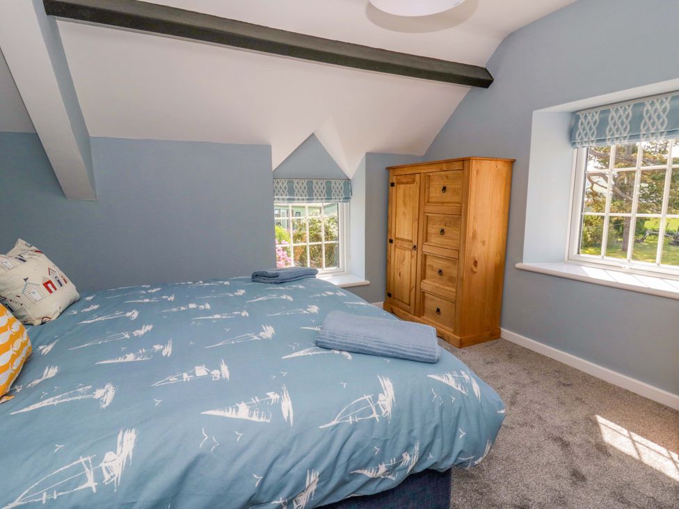 A bedroom with a bed and wardrobe at Rosemary Cottage 1 Tywyn