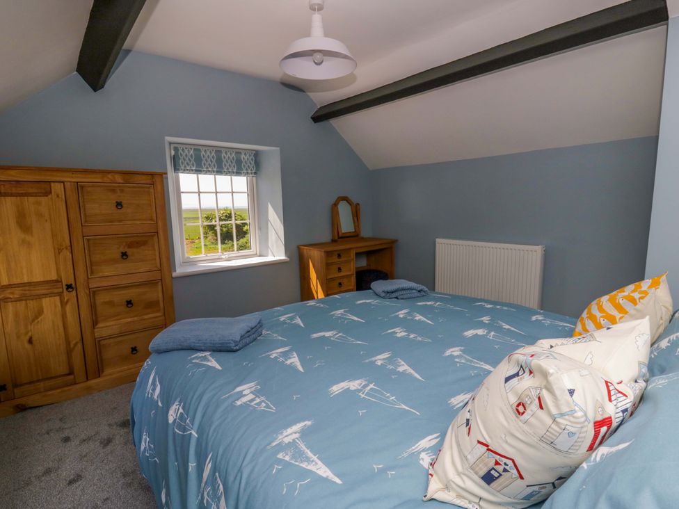 A bedroom with a bed and wooden furniture at Rosemary Cottage 1 Tywyn