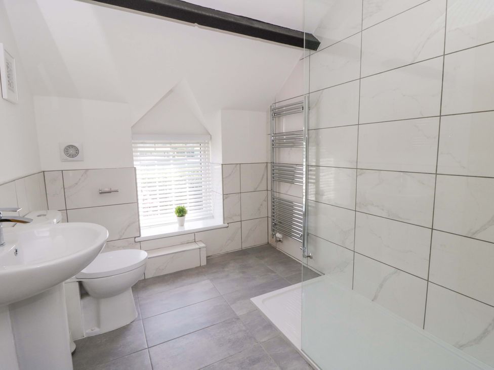 A bathroom with a sink, toilet, shower and towel radiator at Rosemary Cottage 1 Tywyn
