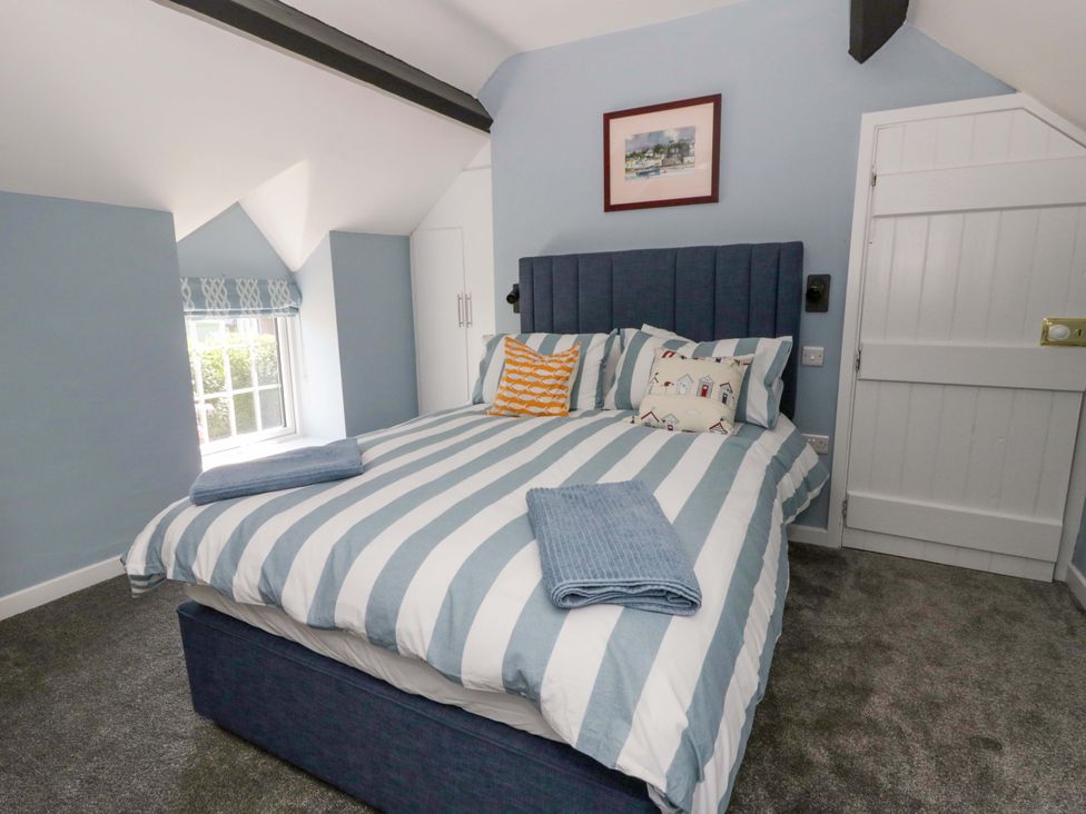 A bedroom with a bed, pillows and a wardrobe at Rosemary Cottage 1 Tywyn
