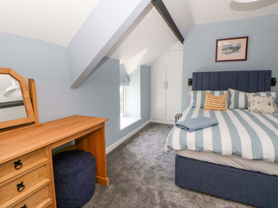 A bedroom with a bed and desk at Rosemary Cottage 1 in Tywyn