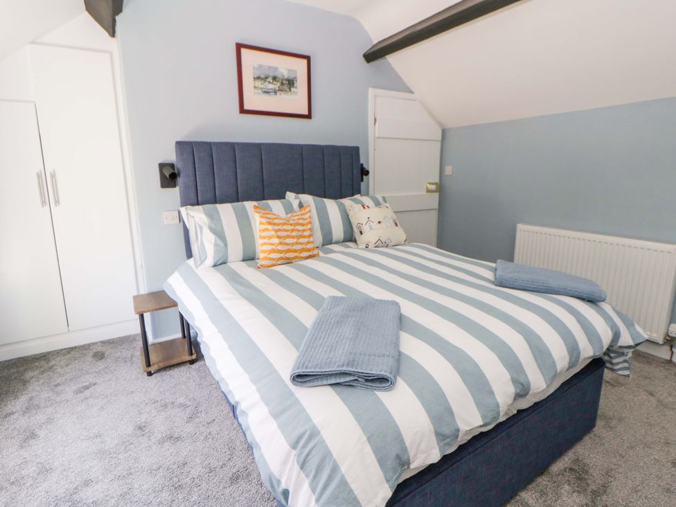 A bedroom with a bed and wardrobe at Rosemary Cottage 1 Tywyn