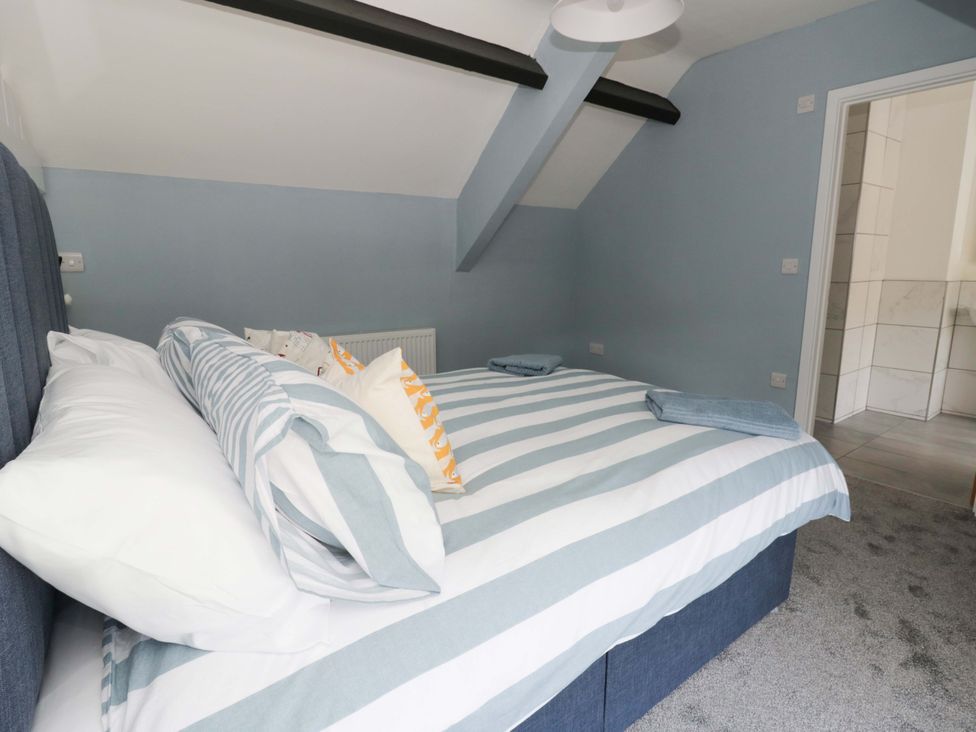 A bedroom with a bed and pillows at Rosemary Cottage 1 in Tywyn
