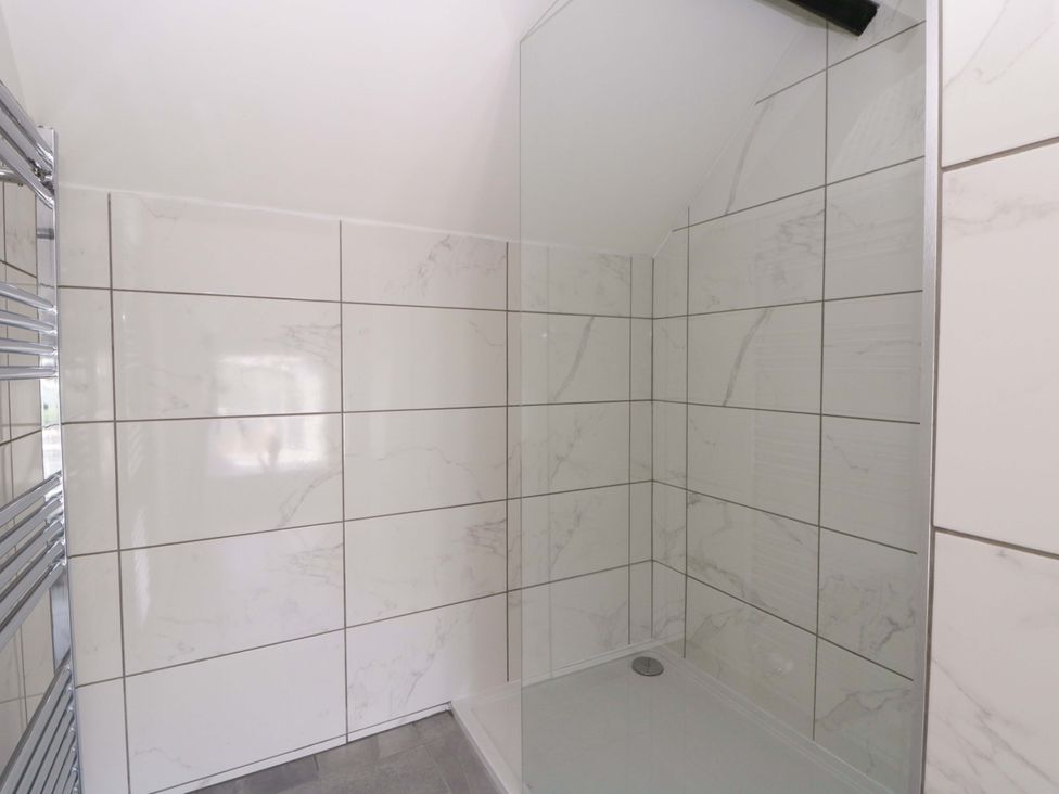 A shower area with tiled walls and a glass screen at Rosemary Cottage 1 Tywyn