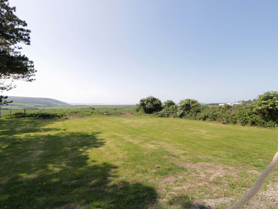 An open garden area with grassy field and trees at Rosemary Cottage 1 Tywyn
