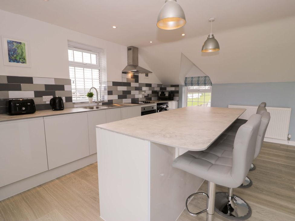 A kitchen with bar stools and a cooker at Rosemary Cottage 2 Tywyn