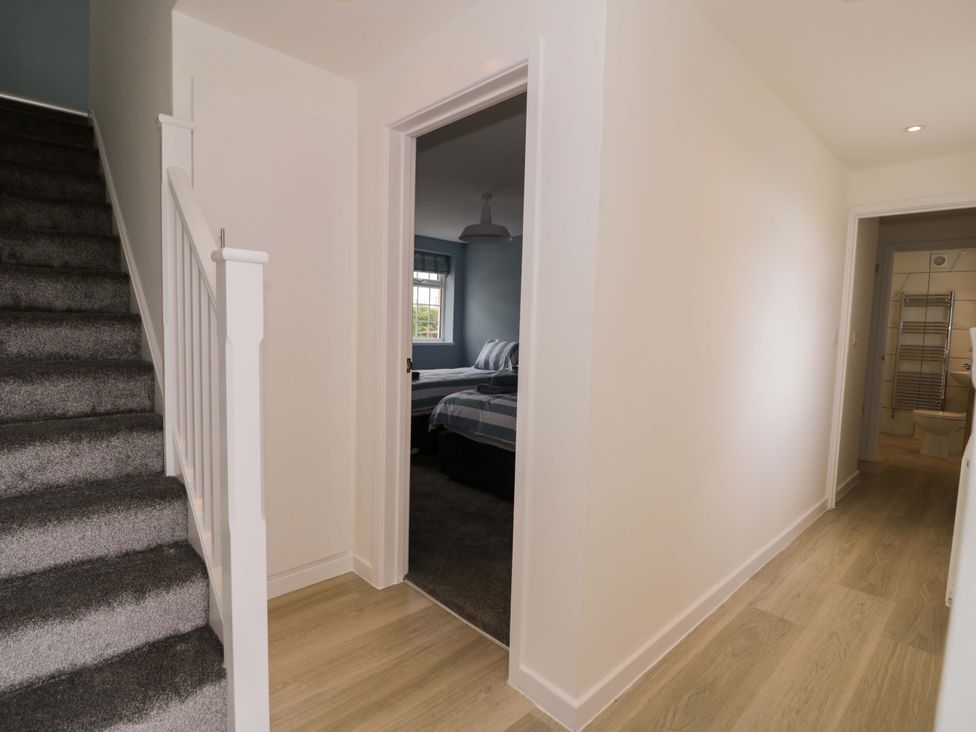 A hallway with stairs and doorways to a bedroom and bathroom at Rosemary Cottage 2 Tywyn
