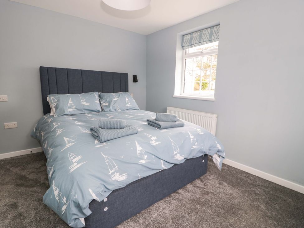 A bedroom with a bed against a wall at Rosemary Cottage 2 Tywyn