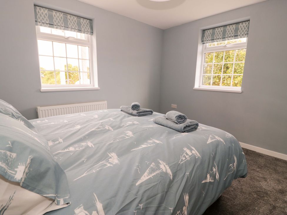 A bedroom with a bed and towels on it at Rosemary Cottage 2 in Tywyn