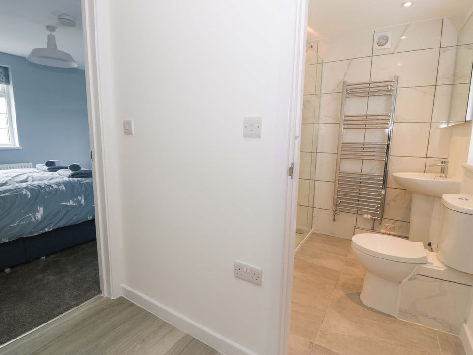 A bathroom with a toilet, sink, and shower visible at Rosemary Cottage 2 Tywyn