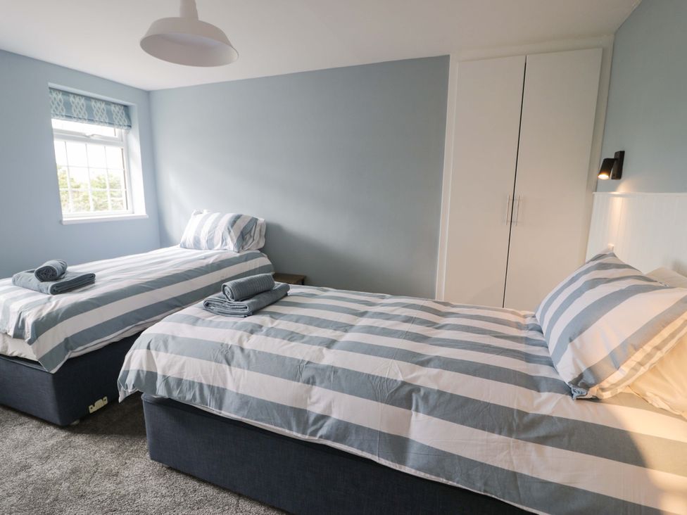 A bedroom with two single beds and a wardrobe at Rosemary Cottage 2 Tywyn