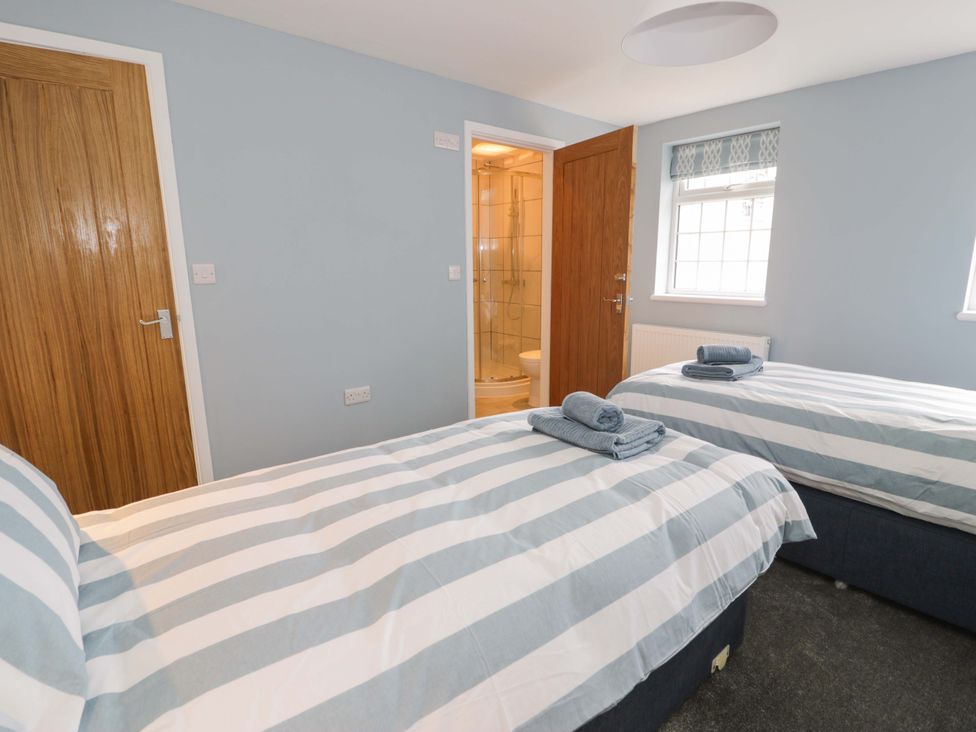 A bedroom with two beds and an adjoining bathroom at Rosemary Cottage 2 in Tywyn