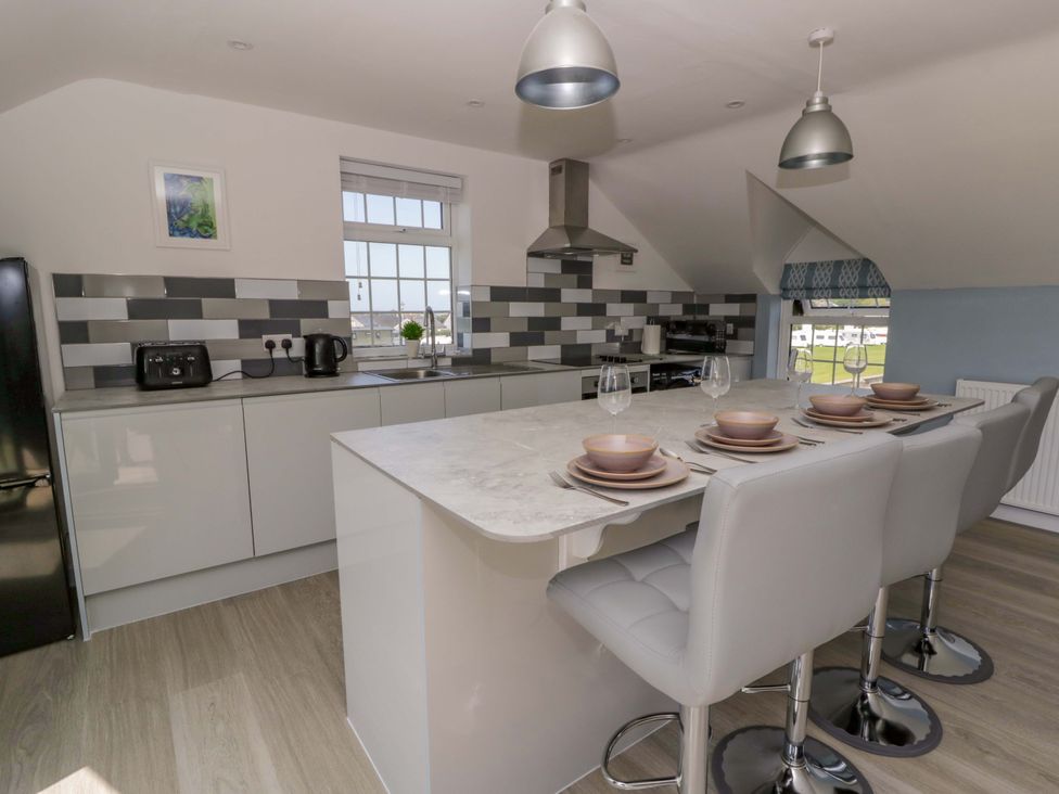 A kitchen with a counter and stools at Rosemary Cottage 2 in Tywyn