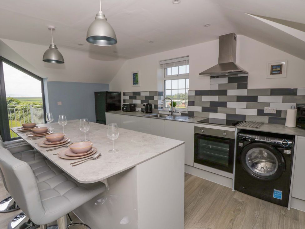 A kitchen with appliances and dining area at Rosemary Cottage 2 Tywyn