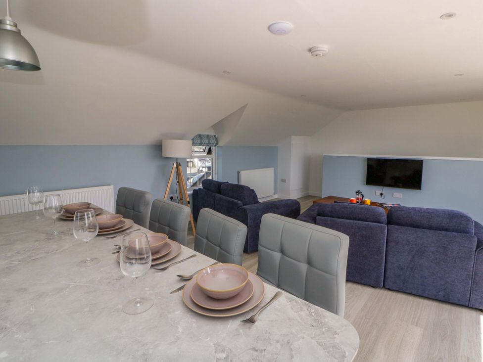 A living room with a table set for dining and a sofa at Rosemary Cottage 2 Tywyn
