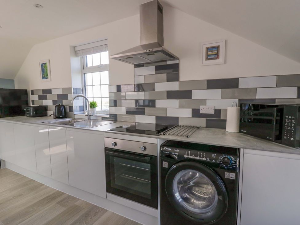 A kitchen with appliances including a microwave and washing machine at Rosemary Cottage 2 Tywyn