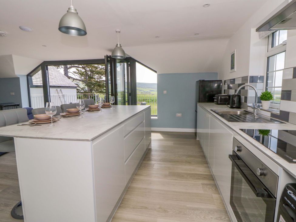 A kitchen with a countertop island and appliances at Rosemary Cottage 2 Tywyn