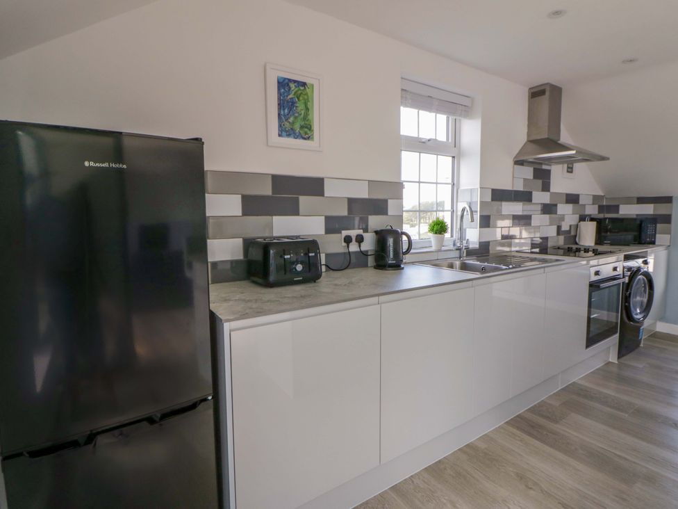 A kitchen with a refrigerator, sink, and stove at Rosemary Cottage 2 in Tywyn
