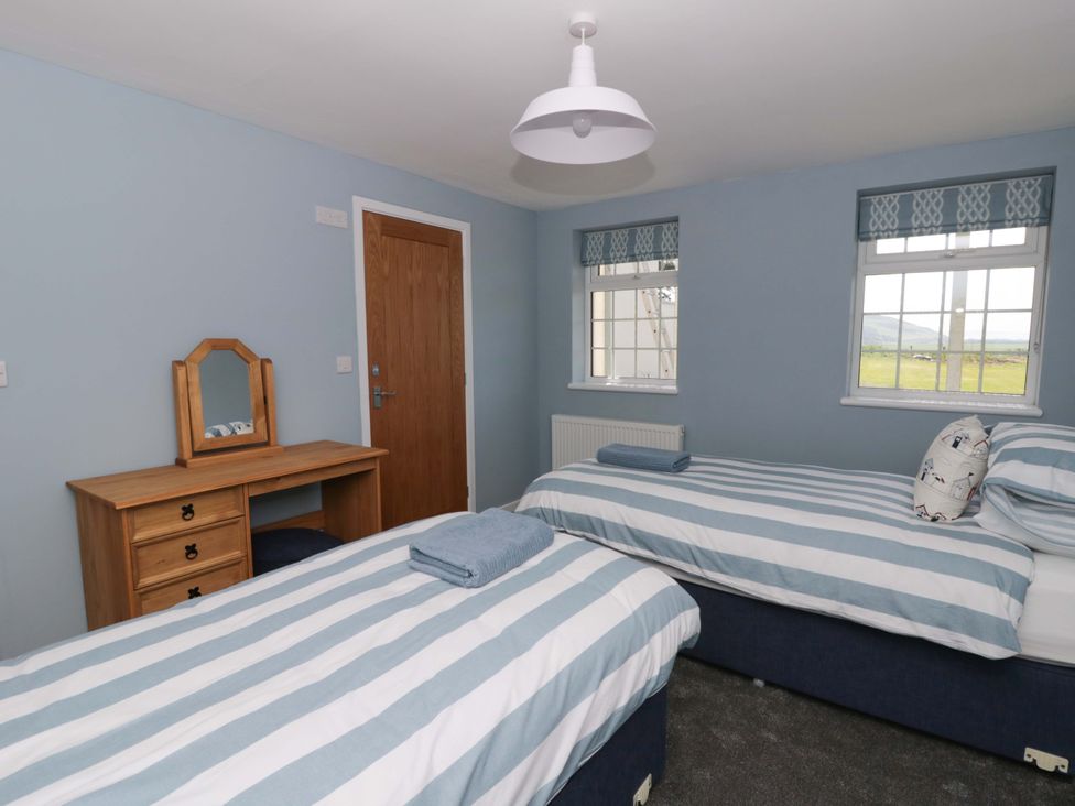 A bedroom with two beds and a dresser at Rosemary Cottage 2 Tywyn