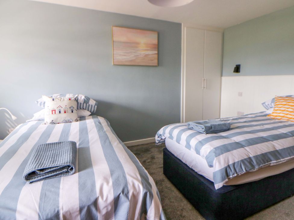 A bedroom with two beds and a painting at Rosemary Cottage 2 Tywyn