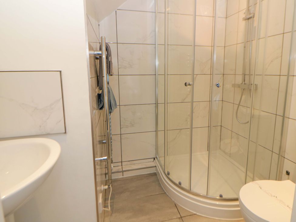 A bathroom featuring a shower, toilet, and sink at Rosemary Cottage 2 Tywyn