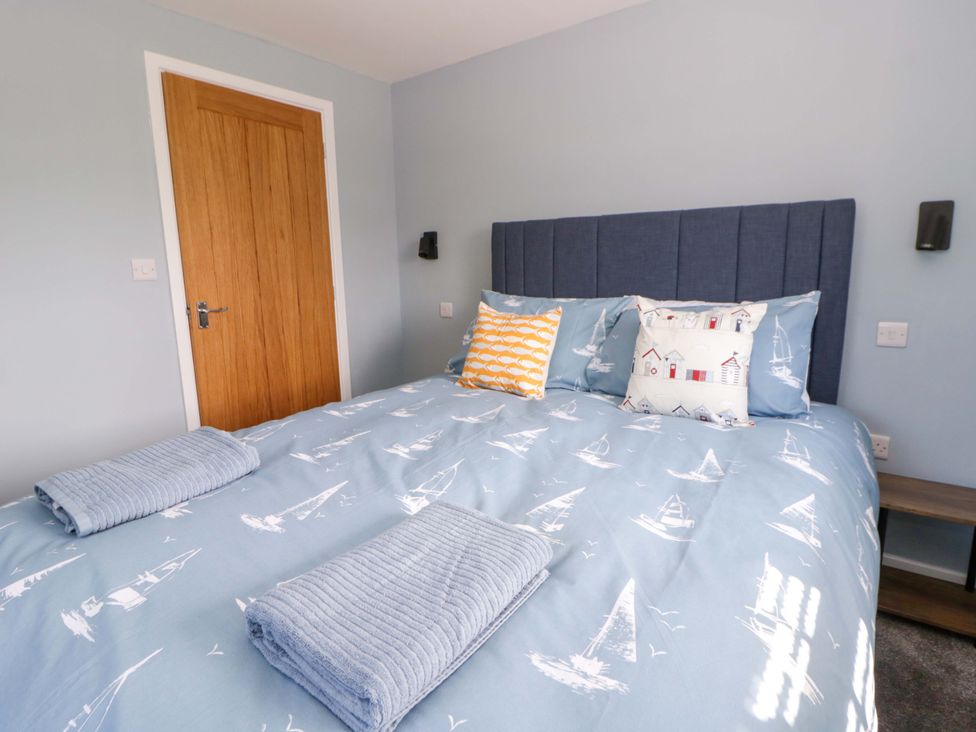 A bedroom with a bed and pillows at Rosemary Cottage 2 Tywyn