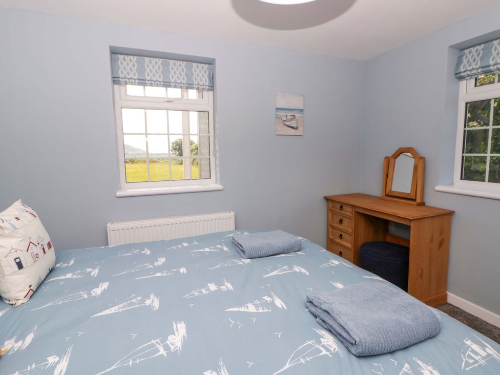 A bedroom with a bed and a desk at Rosemary Cottage 2 Tywyn