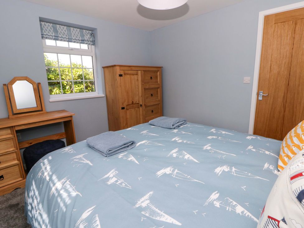 A bedroom with a bed and wooden furniture at Rosemary Cottage 2 Tywyn