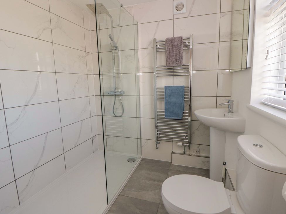 A bathroom with a shower, sink, and toilet at Rosemary Cottage 2, Tywyn
