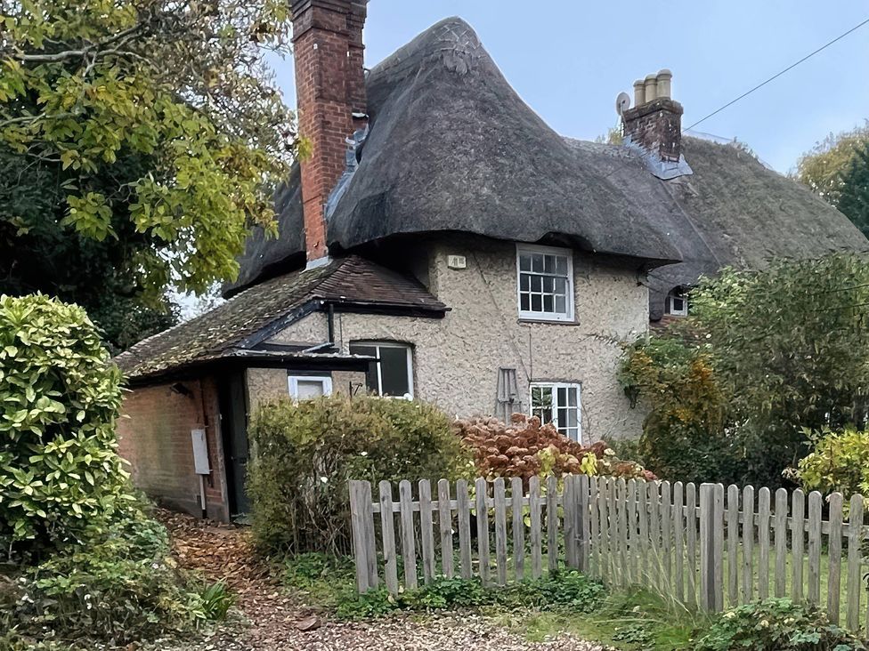 A thatched cottage with a pathway and fence at 16 Bones Lane Petersfield