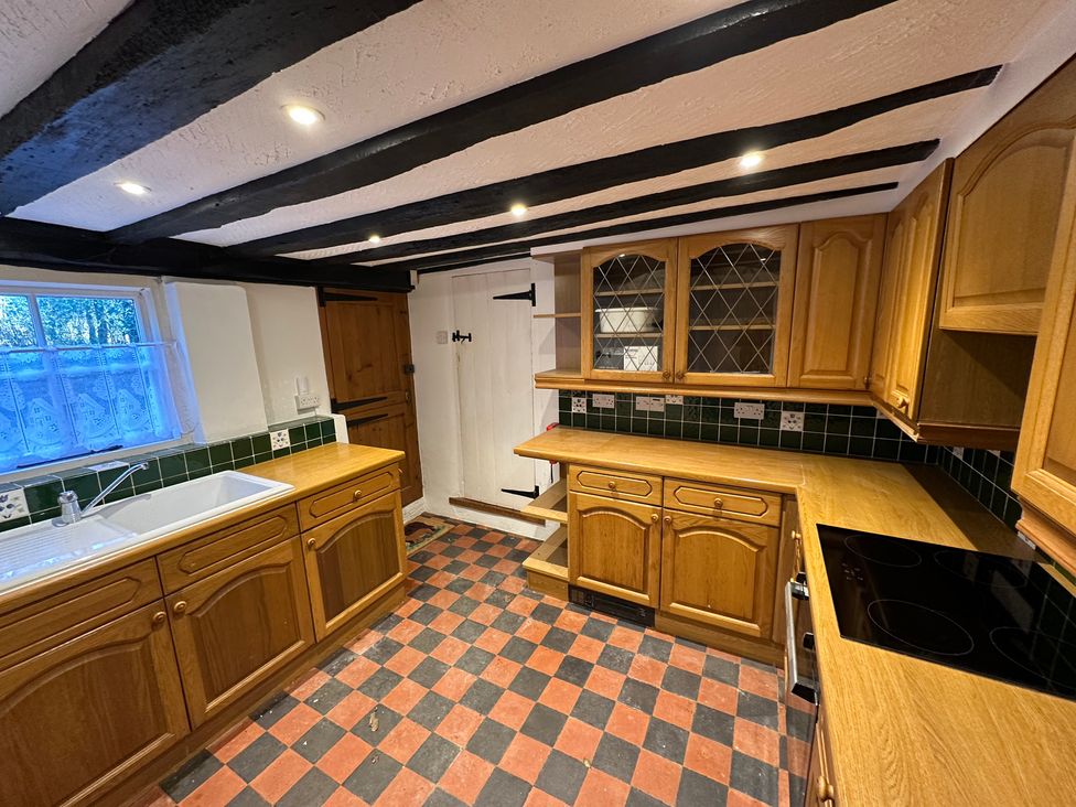 A kitchen with wooden cabinets and a sink at Hop Cottage in Petersfield