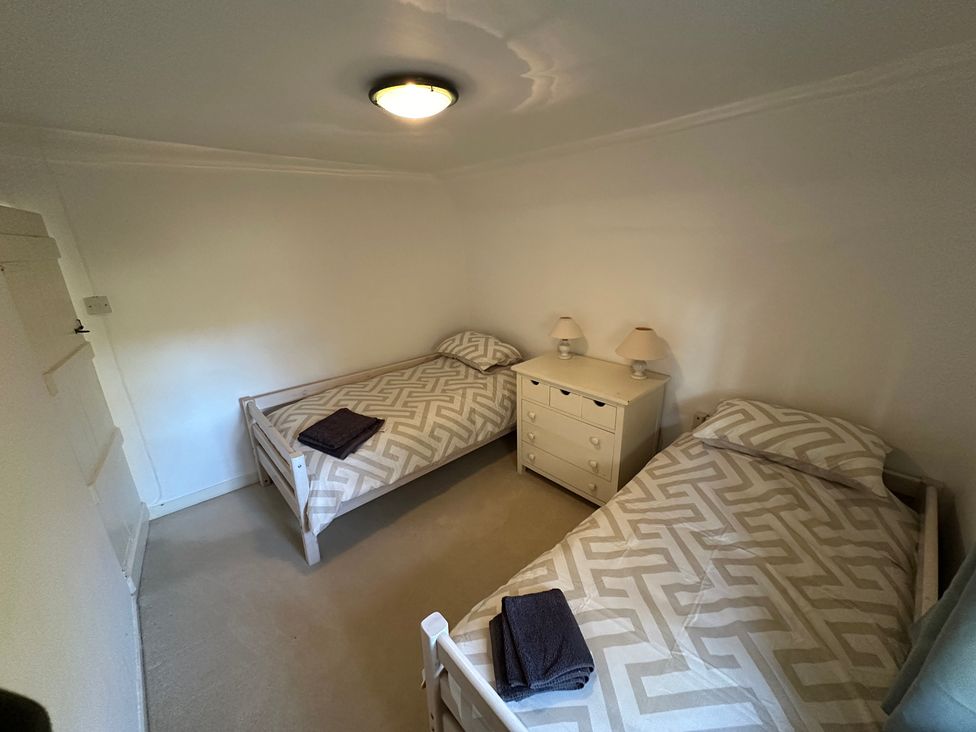 A bedroom with two beds and a chest of drawers at Hop Cottage in Petersfield