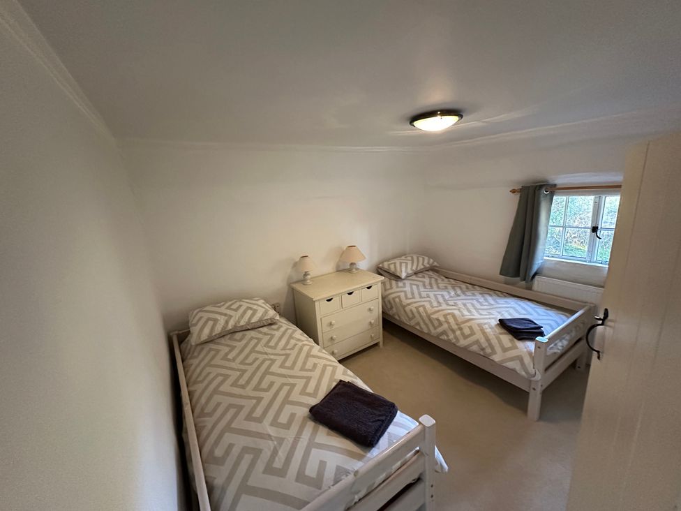 A bedroom with two beds and a nightstand at Hop Cottage Petersfield