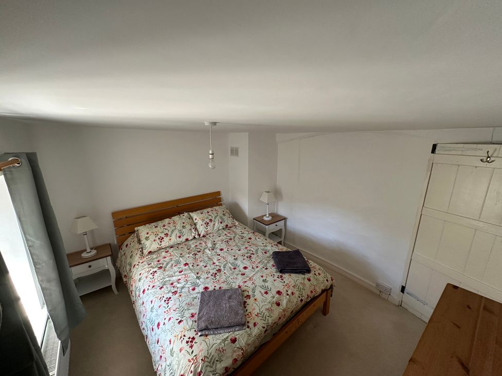 A bedroom with a bed and nightstand at Hop Cottage in Petersfield