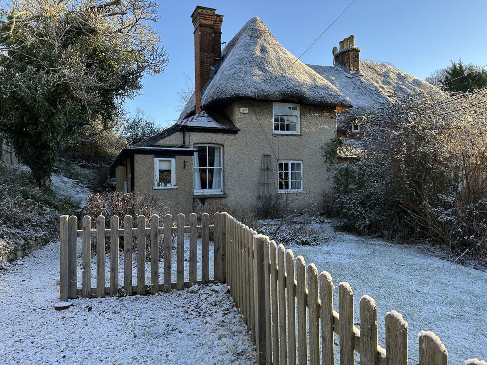 A cottage with a thatched roof and garden at Hop Cottage in Buriton